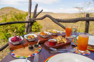 a table with plates of food and drinks on it at Loisaba Star Beds in Tura
