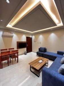 uma sala de estar com um sofá azul e uma mesa em سجى للوحدات السكنية em Abha