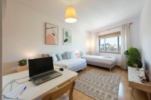 ein Wohnzimmer mit einem Laptop auf einem Schreibtisch in der Unterkunft Boavista Boho Apartment w/ Garage in Porto