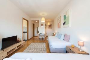 ein Wohnzimmer mit 2 Betten und einem Flachbild-TV in der Unterkunft Boavista Boho Apartment w/ Garage in Porto