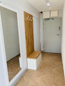 een lege kamer met een deur en een houten bank bij West Pomeranian Apartments Wielka Odrzańska SZCZECIN in Szczecin