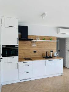 een keuken met witte kasten en een houten aanrecht bij West Pomeranian Apartments Wielka Odrzańska SZCZECIN in Szczecin