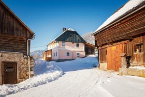 eine schneebedeckte Straße neben einem Holzgebäude in der Unterkunft Ferienhaus Schwöllerbauer in Sankt Martin am Grimming