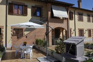 a patio with a table and an umbrella and a grill at La Loggina in Tuoro sul Trasimeno
