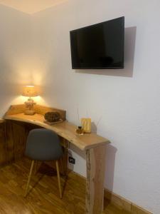 einen Schreibtisch mit Stuhl und einen TV an der Wand in der Unterkunft Hotel Coeur Du Village in La Thuile