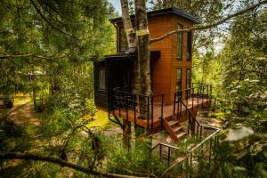 a tree house with a deck in the woods at Domek na drzewie - Na Łośmiu Metrach in Grudki