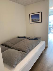 Bett in einem weißen Zimmer mit einem Bild an der Wand in der Unterkunft Pakhuset Anholt in Anholt