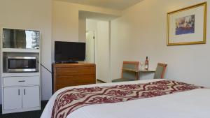 a hotel room with a bed and a flat screen tv at Valley Star Motel in Penticton