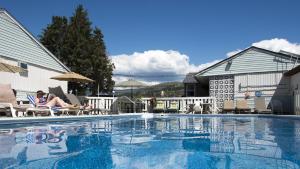 a woman sitting in a chair next to a swimming pool at Valley Star Motel in Penticton