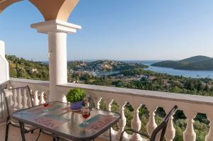 a table on a balcony with a view of the water at Charoula's Apartments in Syvota