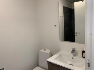 La salle de bains blanche est pourvue d'un lavabo et d'un miroir. dans l'établissement Pakhuset Anholt, à Anholt