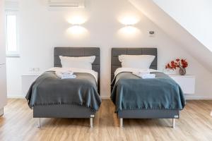 two beds in a room with white walls and wood floors at Diana Boardinghouse KONTAKTLOSER SELF CHECK IN & SELF CHECK OUT in Erzhausen