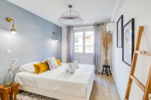 una camera da letto bianca con un letto con cuscini gialli di Appartement Wilsonia - Welkeys a Antibes
