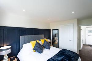 a bedroom with a large bed with yellow and black pillows at 10 Boskenza Court in Carbis Bay