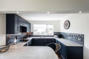 a kitchen with black cabinets and a table and a clock at 10 Boskenza Court in Carbis Bay