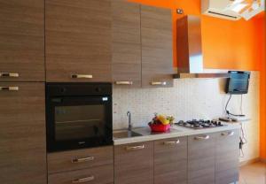 a kitchen with wooden cabinets and a stove top oven at Appartamento con terrazzo sul mare. in Capo Rizzuto