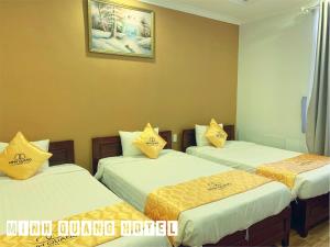 um quarto com 3 camas com almofadas amarelas em Khách sạn Minh Quang em Phan Rang-Tháp Chàm