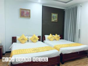 a bedroom with two beds with yellow pillows at Khách sạn Minh Quang in Phan Rang