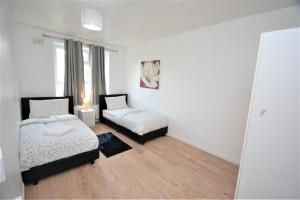 um quarto com 2 camas e uma janela em Beautiful London 2 Bedroom Flat near Finsbury Park em Londres