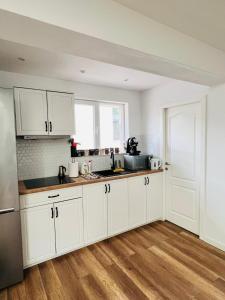 a kitchen with white cabinets and a wooden floor at Master Adventure Guest House in Vadul lui Carol II