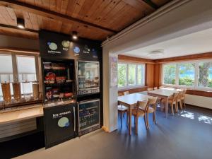 um restaurante com uma mesa e cadeiras e um frigorífico em Brienz Youth Hostel em Brienz