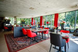 un restaurant avec des chaises rouges, des tables et des fenêtres dans l'établissement Bastion Hotel Utrecht, à Utrecht