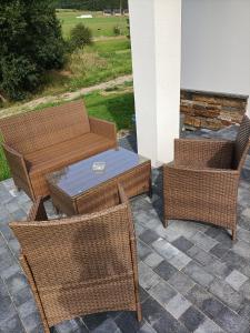 a patio with two wicker chairs and a table at Modrzewiowa Ostoja in Kluszkowce
