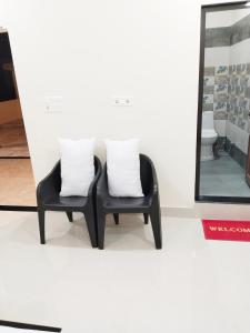 zwei schwarze Stühle mit weißen Kissen neben einem Spiegel in der Unterkunft Airport Luxury Nature Valley Homestay in Doiwāla
