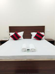 Airport Luxury Nature Valley Homestay في Doiwāla: غرفة نوم بسرير أبيض ومخدات حمراء وسوداء