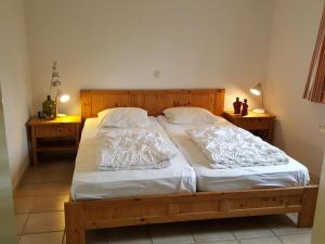 1 dormitorio con cama de madera con sábanas y almohadas blancas en Mees, en Hollum