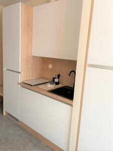 Una cocina con gabinetes blancos y un fregadero. en LikeDaheim Apartments, en Rosbach vor der Höhe
