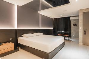 a bedroom with a large bed and a table at Drops Motel Porto Alegre in Porto Alegre