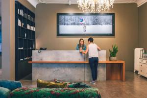 a man and a woman standing at a reception desk at Bellevue-Terminus - Urban Lifestyle Hotel in Engelberg