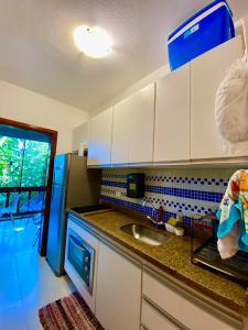 uma cozinha com armários brancos e um lavatório em Housing 31 - Cond. Mata Azul - frente á entrada 18 em São Sebastião