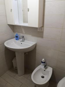 La salle de bains blanche est pourvue d'un lavabo et de toilettes. dans l'établissement Casa Marconi, à Aragona