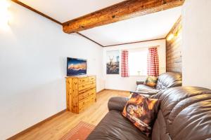 ein Wohnzimmer mit einem Ledersofa und einem TV in der Unterkunft Ferienhaus Schwöllerbauer in Sankt Martin am Grimming