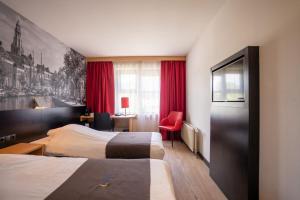 a hotel room with two beds and a red chair at Bastion Hotel Groningen in Groningen