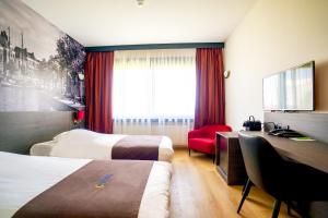 Cette chambre comprend deux lits et un bureau. dans l'établissement Bastion Hotel Groningen, à Groningue