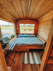 a bed in a tiny house with a window at Brīvdienu namiņi Kalnozoli in Indrāni