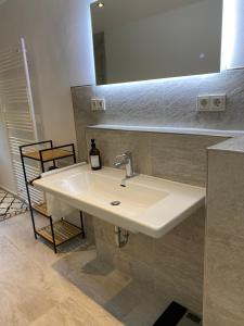lavabo blanco en el baño con espejo en Sonnenlay Lounge - Studio & Ferienhaus, en Brauneberg