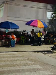 Tambo Hostel في ليتيسيا: مجموعة أشخاص يجلسون تحت المظلات في شارع