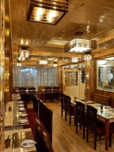 un restaurante con suelo de madera, mesas y sillas en Hotel Zingkham Residency en Gangtok