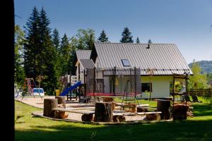 een speeltuin voor een huis met een gebouw bij Domki Pod Lasem MM in Rabka