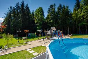 een zwembad met een speeltuin en een glijbaan bij Domki Pod Lasem MM in Rabka