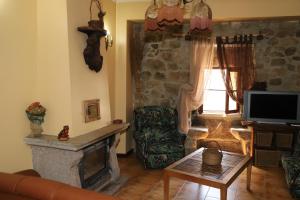 a living room with a stone fireplace and a television at Casa na Serra da Estrela in Melo