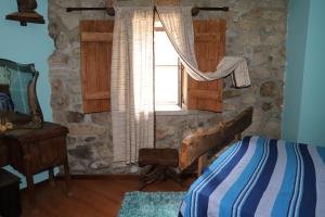 a bedroom with a bed and a window in a stone wall at Casa na Serra da Estrela in Melo