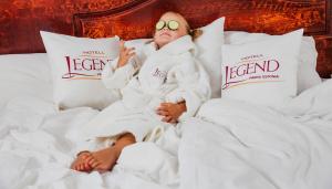 a woman laying in bed wearing towels and sunglasses at Hotel Legend in Pärnu
