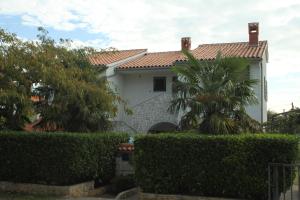 una casa blanca con una palmera delante de ella en Family friendly apartments with a swimming pool Valbandon, Fazana - 7346, en Fažana