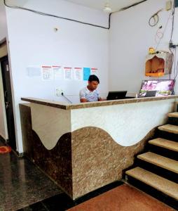 un hombre sentado en un mostrador con un portátil en Hotel Krishna Palace & Restaurant By WB Inn, en Agra