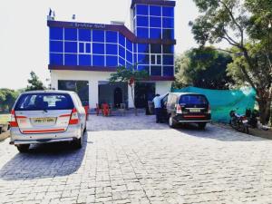 dos autos estacionados frente a un edificio azul en Hotel Krishna Palace & Restaurant By WB Inn, en Agra